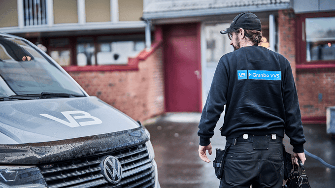 Rørlegger med verktøykasse på vei fra bilen til et borettslag