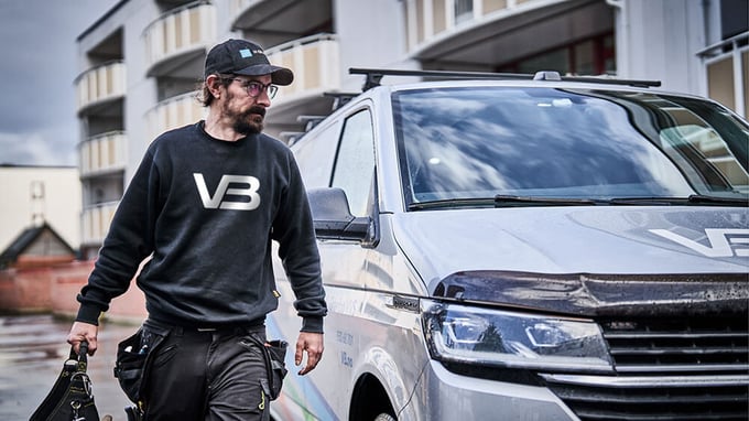 Rørlegger fra VB med verktøykasse i hånda på vei fra bilen og inn i et borettslag.