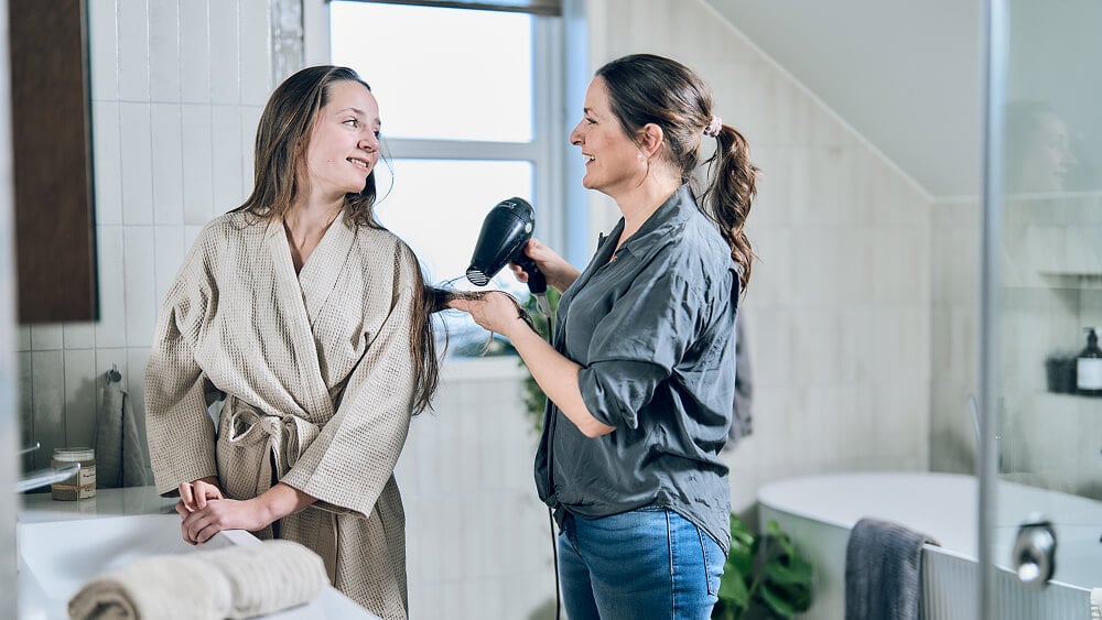 To kvinner som ser på hverandre og smiler på et moderne baderom