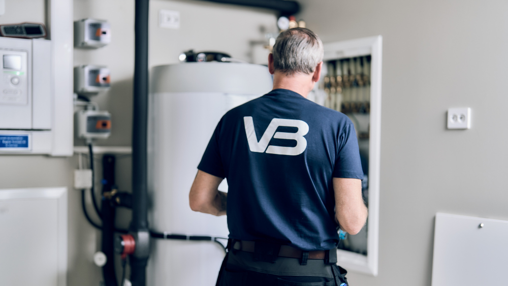 Ryggen til en rørlegger som installerer en varmtvannsbereder 