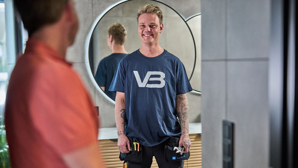 VB-rørlegger som smiler og prater med en kunde på et pent bad
